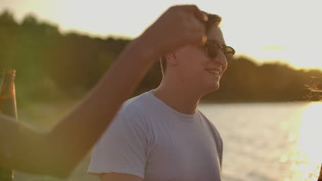 A-brutal-boy-celebrates-a-birthday-with-the-best-friends.-This-is-carefree-open-air-party-with-beer-on-the-beach-near-the-lake-coast-at-sunset.